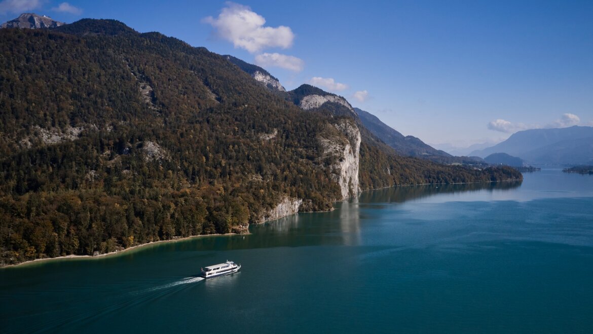 Loď WolfgangseeSchifffahrt na jezeře Wolfgangsee s horami Salzkammergut v pozadí (Zvětšený pohled)
