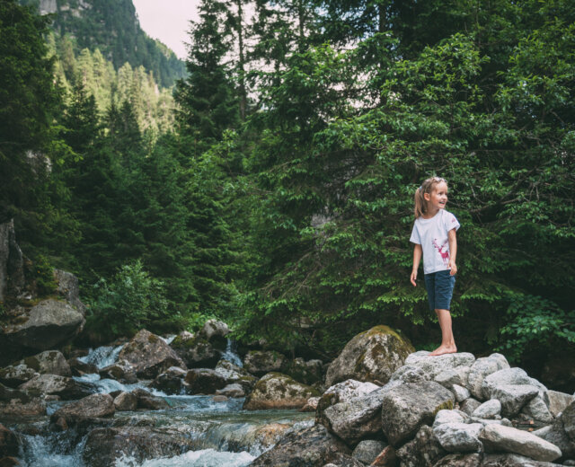 Dívka stojí na kamenech u potoka v Národním parku Vysoké Taury