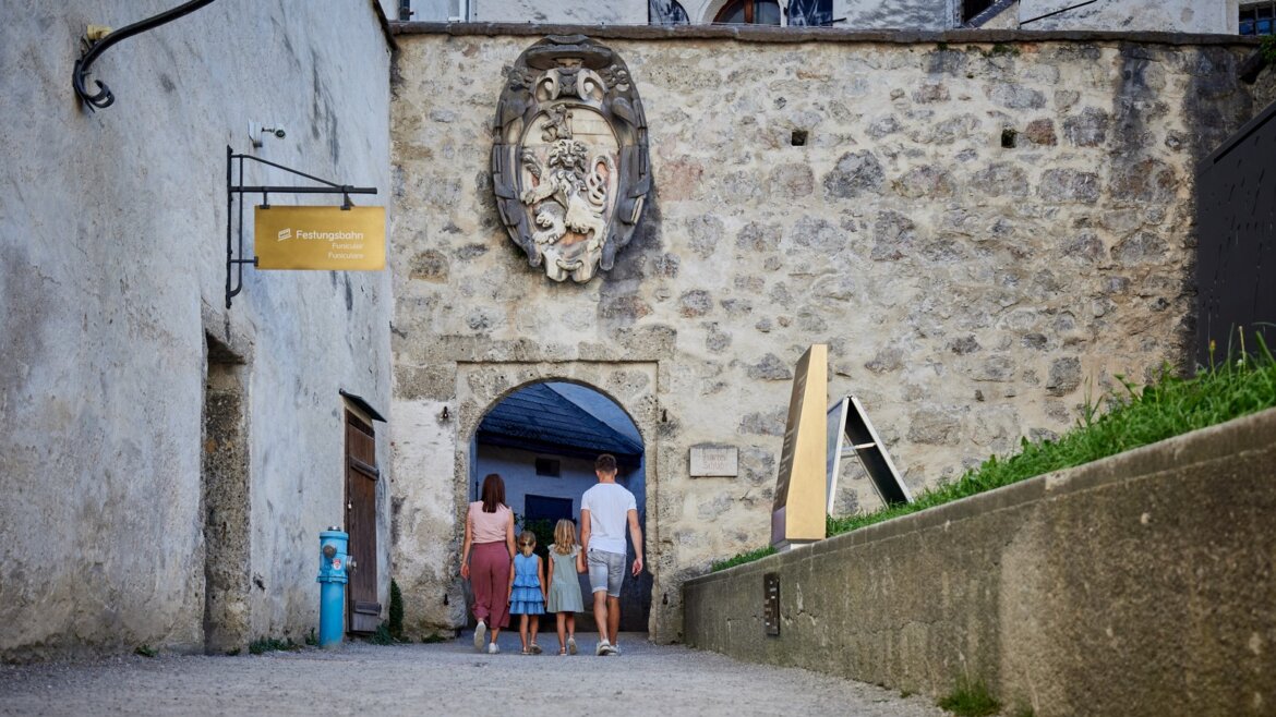 Rodina prochází kamenným obloukem z Festungsbahn Hohensalzburg. (Zvětšený pohled)