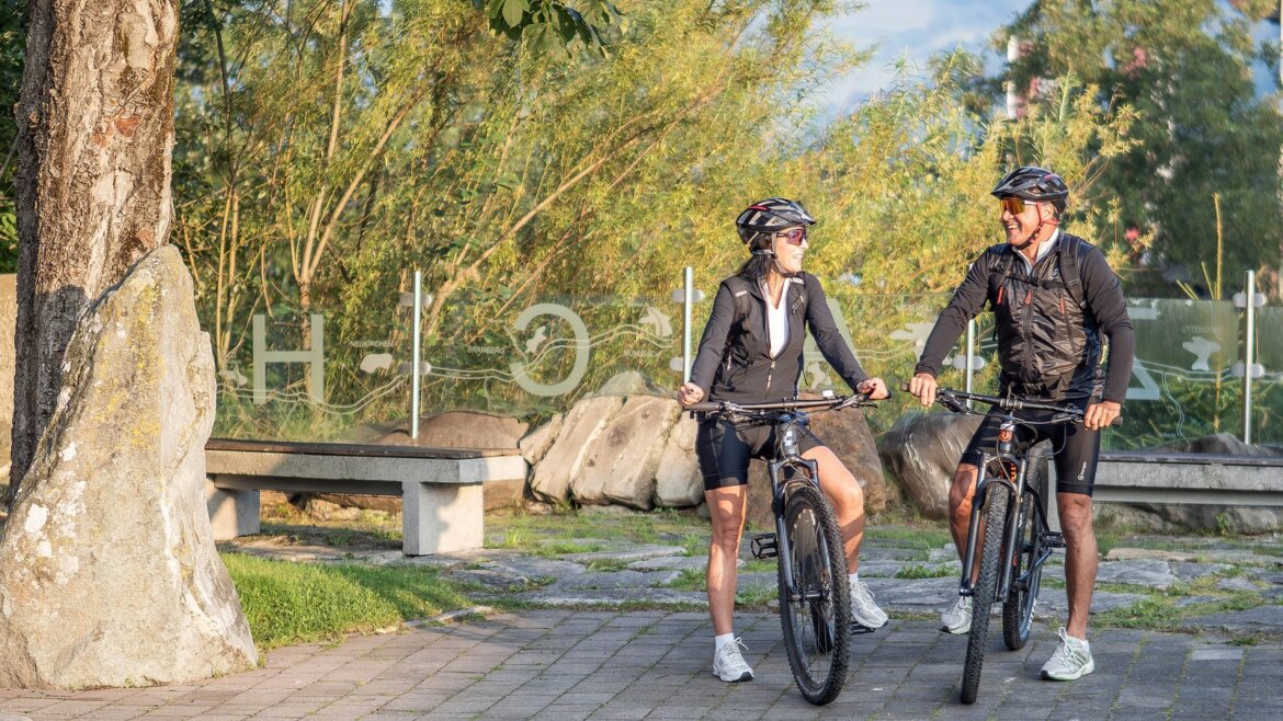 Dva lidé na kole v helmách v oblasti Piesendorf-Niedernsill, kudy prochází Tauernradweg (Zvětšený pohled)