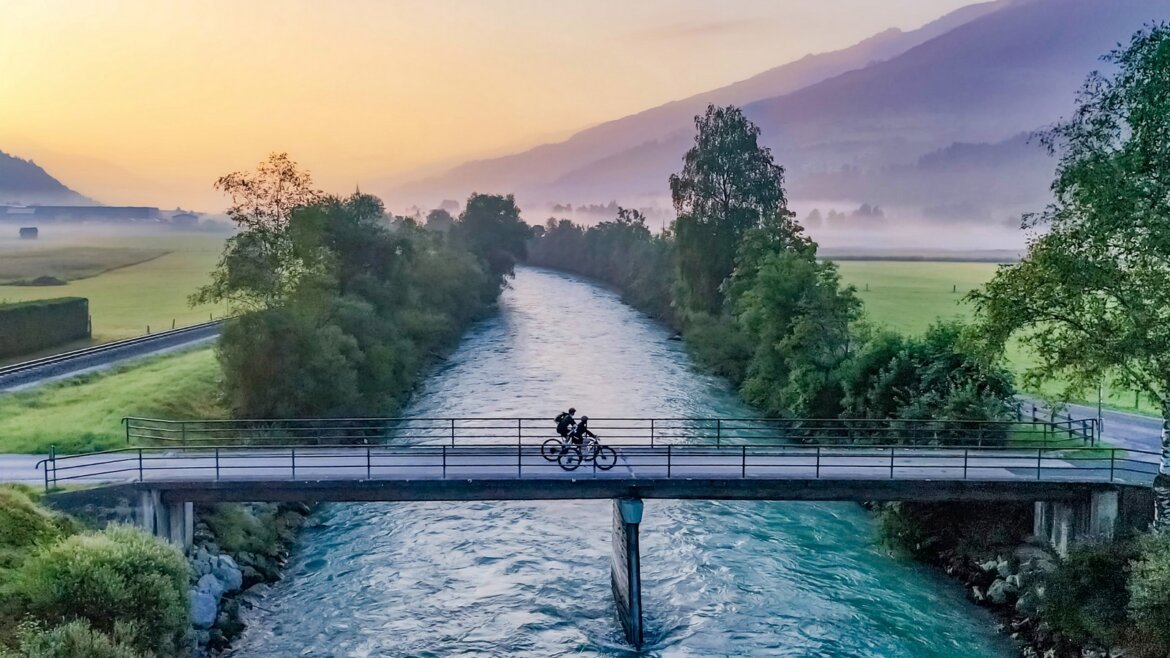 Dva cyklisté přejíždějí most přes Salzach na trase Tauernradweg (Zvětšený pohled)