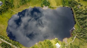 Tmavé slatinné jezero Prebersee z ptačí perspektivy. Vpravo dole je vidět střelnice