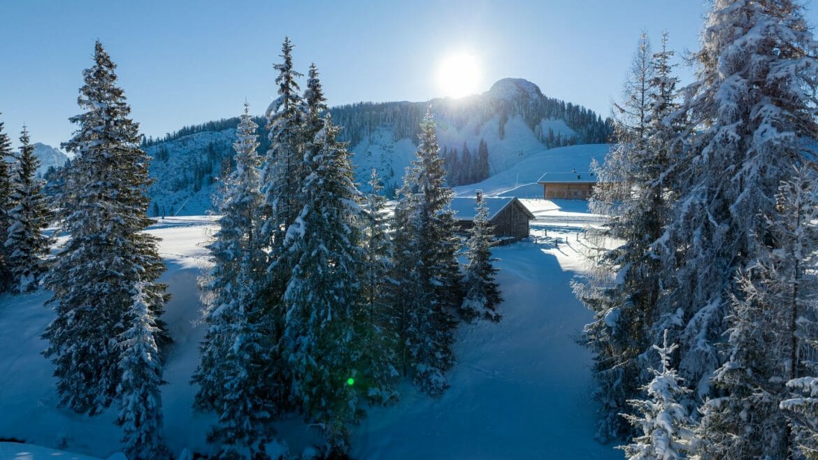 Slunce zapadá za zasněženou horu v lyžařské oblasti Almenwelt Lofer