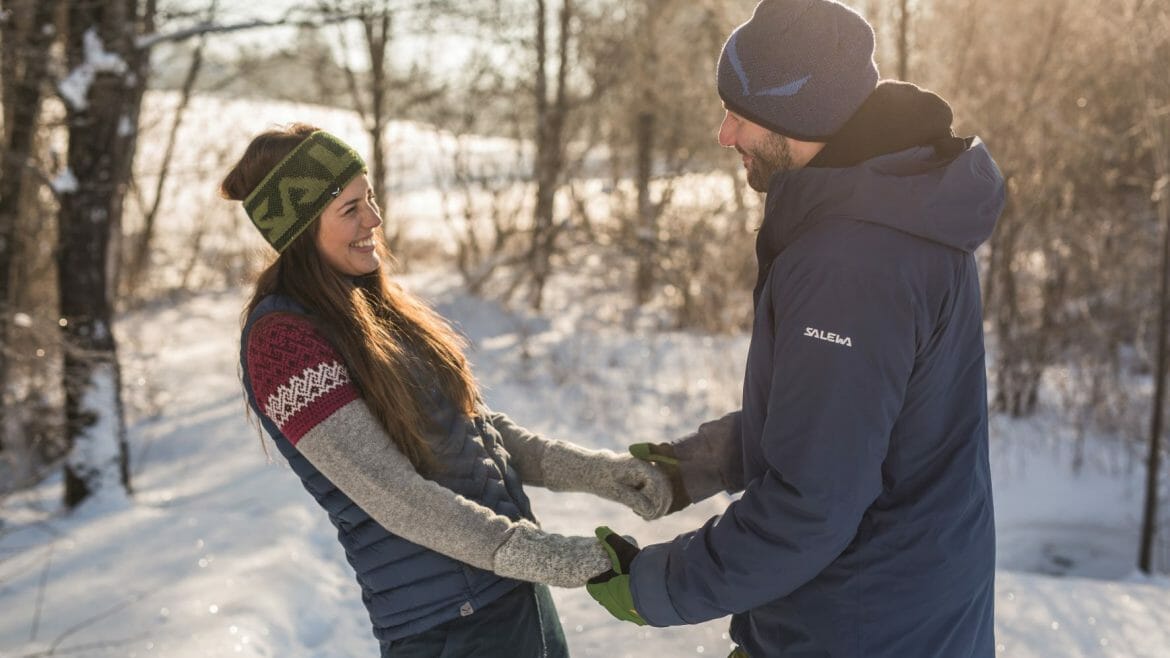 Pár se drží za ruce na vycházce zasněženou zimní krajinou v Salcburském Saalachtalu