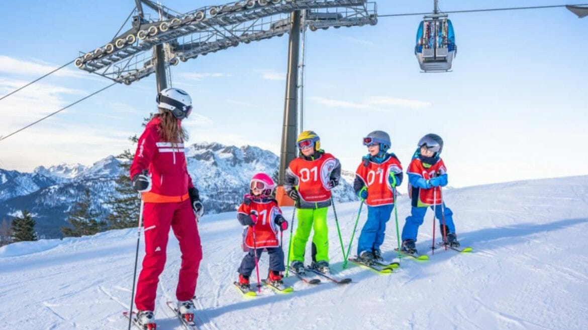 Instruktorka lyžování učí skupinu čtyř dětí, jak se bezpečně pohybovat na zasněžených svazích 