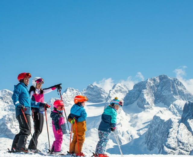 dachstein-west-skifamilie_im-hintergrund-dachstein-1200×675 Prosluněné sjezdovky s výhledem na panorama horského masivu v Dachstein-West