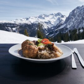 Knedlíky se zelím a oblohou na terase s výhledem na zasněžené hory Dachstein West