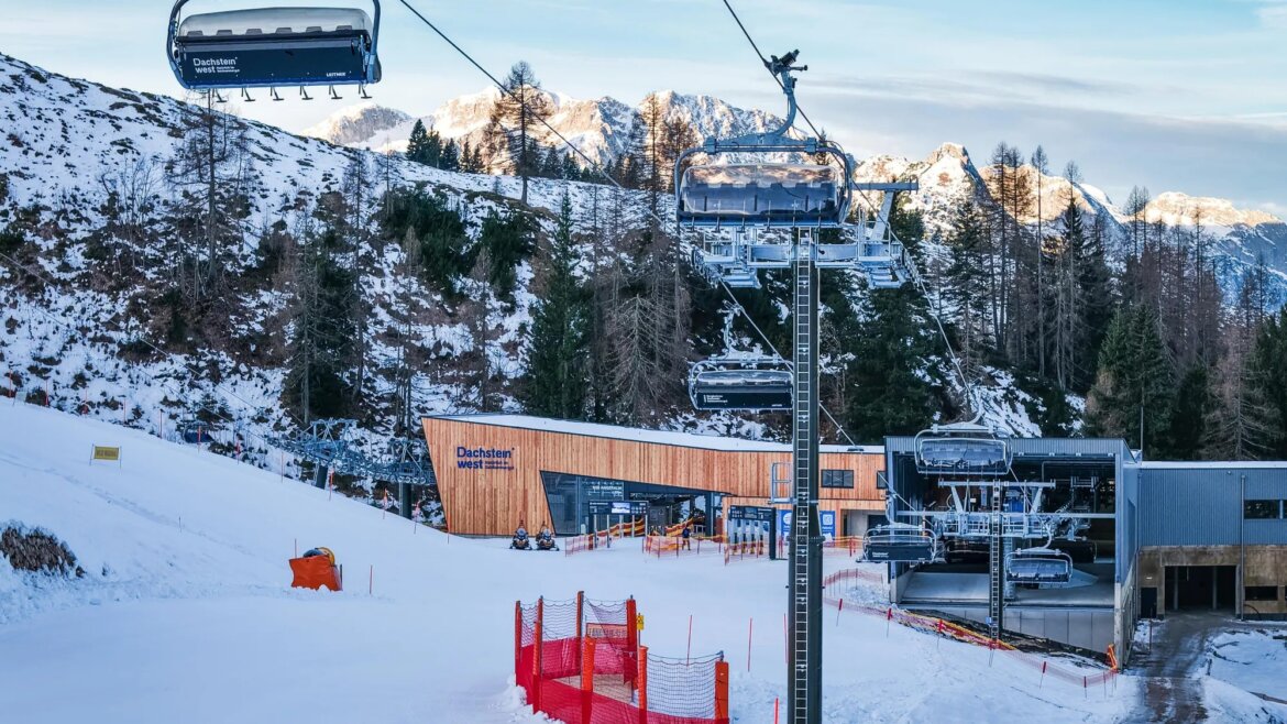 Lanovka nad sjezdovkou v lyžařském středisku Dachstein West s budovou stanice v pozadí.
