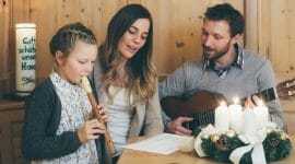 Tatínek na kytaru, maminka zpívá, dcera hraje na flétnu u stolu s adventním věncem koledu Tichá noc, svatá noc.