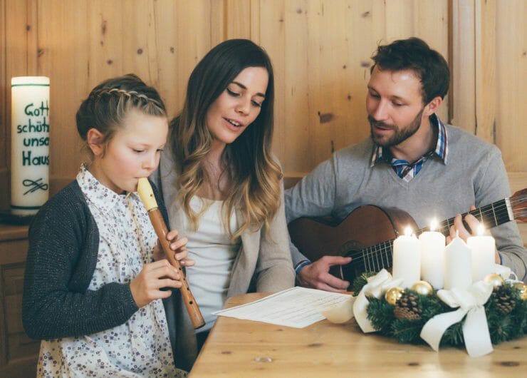 Tatínek na kytaru, maminka zpívá, dcera hraje na flétnu u stolu s adventním věncem koledu Tichá noc, svatá noc.