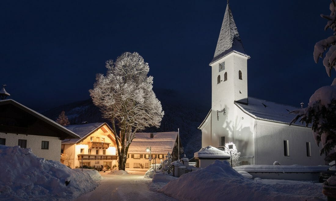 Večerní pohled na osvětlený kostel v Hintersee v Salcbursku 
