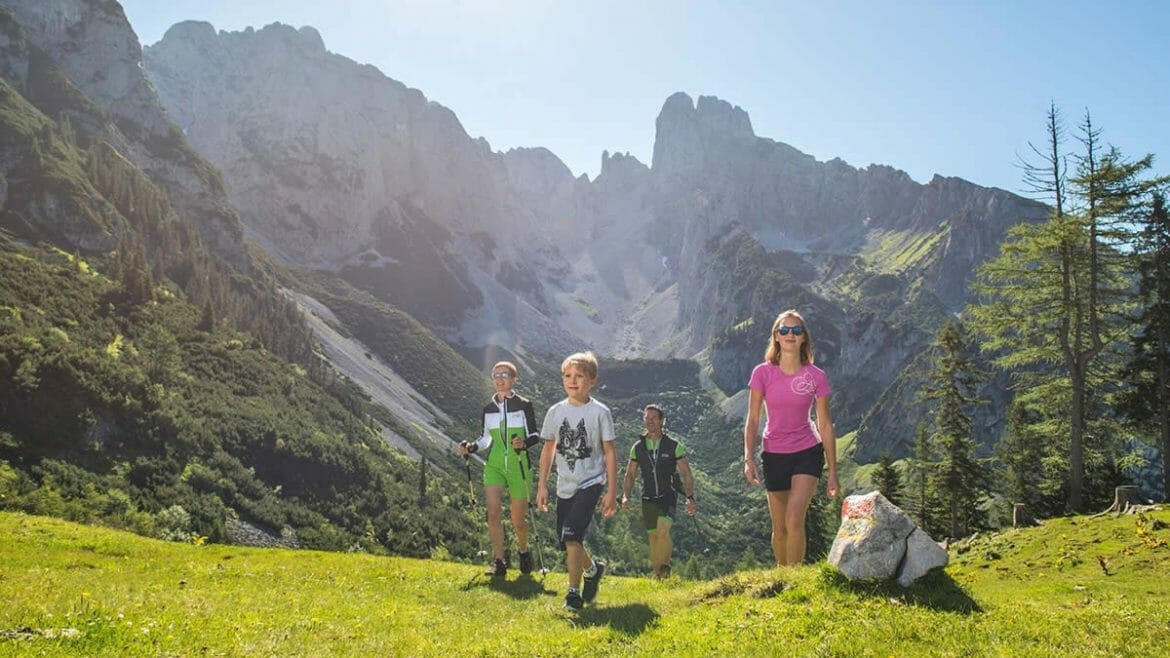 Výlet s dětmi po zelených horských pastvinách v regionu Dachstein West a pohled na horu Bischofsmütze