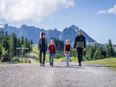 Čtyřčlenná rodina jde společně po štěrkové cestě během rodinné dovolené v Dachstein West.