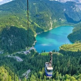 Lanovka Gosaukammbahn nad modrým jezerem a zelenými vrcholky jehličnanů