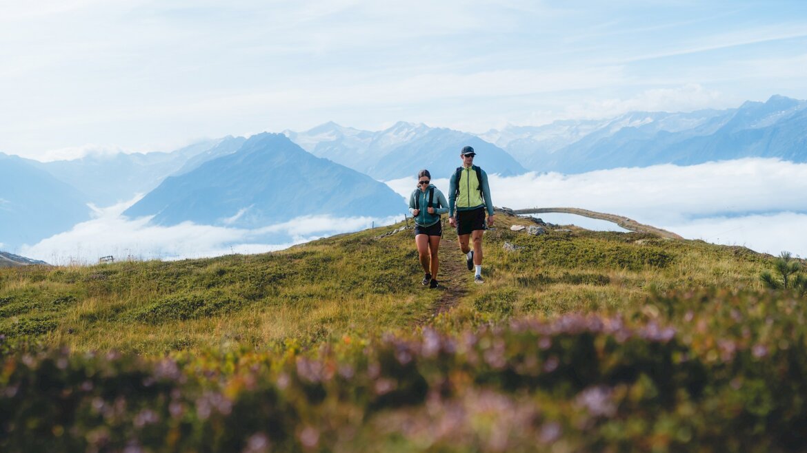 Dvě osoby na túře v Léto Wildkogel-Arena Neukirchen Bramberg s malebným výhledem na hory a mraky. (Zvětšený pohled)