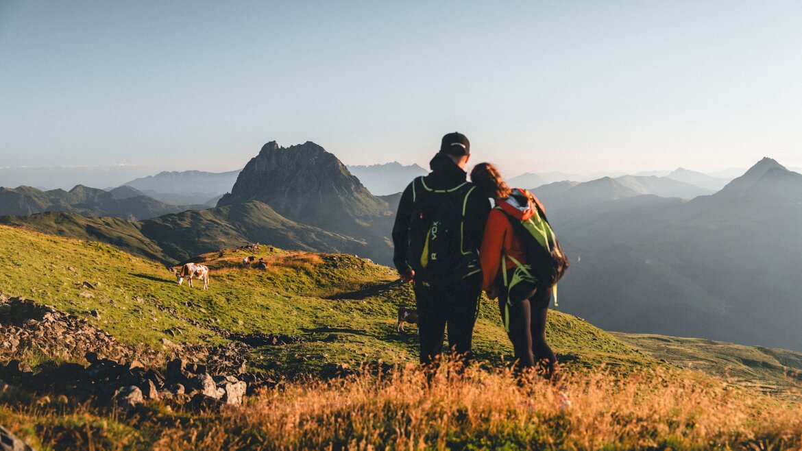 Dvojice s batohy na zádech pozoruje vrcholy při západu slunce v Léto Wildkogel-Arena Neukirchen Bramberg. (Zvětšený pohled)