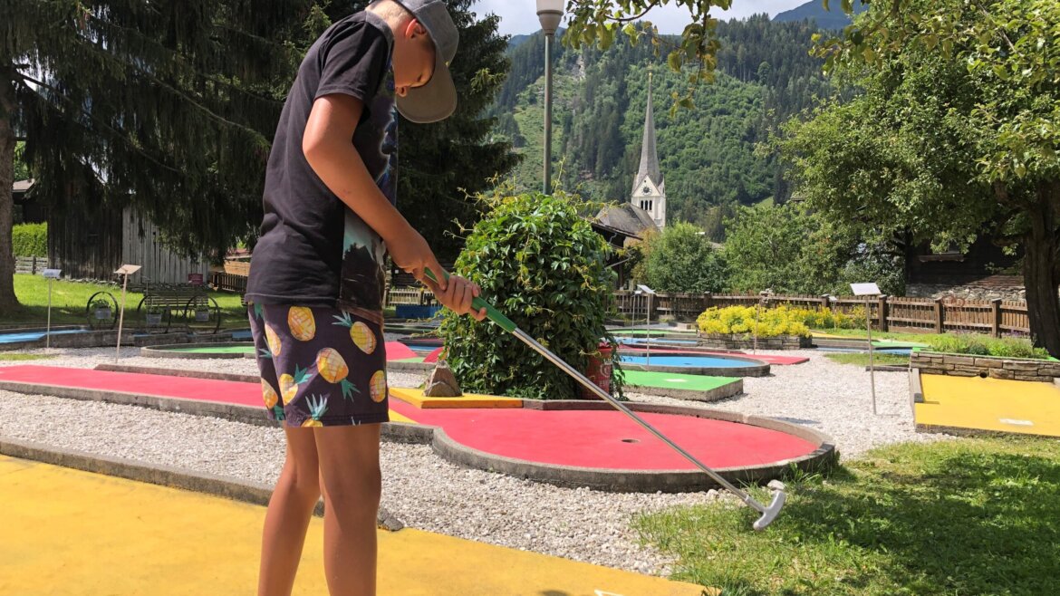 Chlapec hraje venku minigolf za slunečného dne v Raurisu (Zvětšený pohled)
