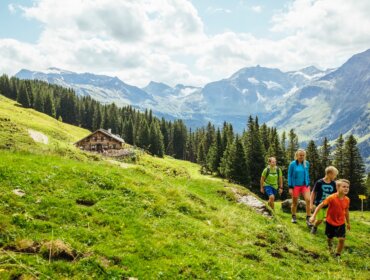 Turisté putují okolo chaty Mitterastenalm na idylickém místě uprostřed Národního parku Vysoké Taury.