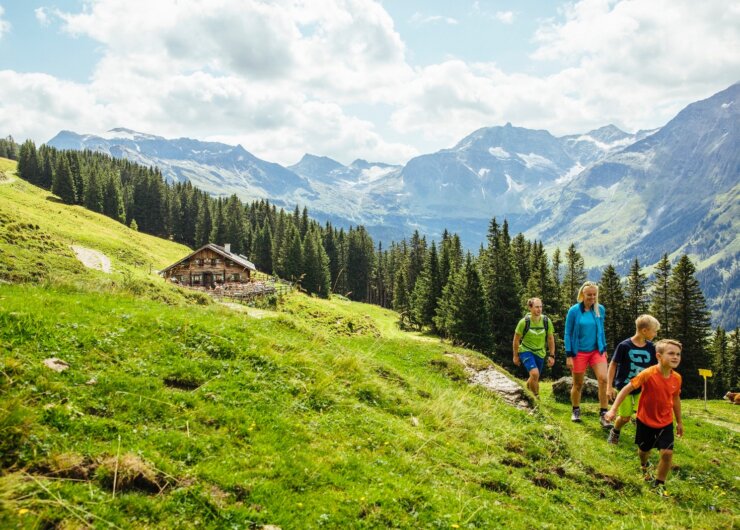 Turisté putují okolo chaty Mitterastenalm na idylickém místě uprostřed Národního parku Vysoké Taury.