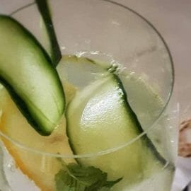 Osvěžující letní drink, gin s tonicem a plátkem salátové okurky ve sklenici doplněné ledem