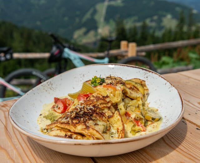 Talíř s bylinkovými palačinkami na stole před chalupou Zachofalm v Dientenu v regionu Hochkönig