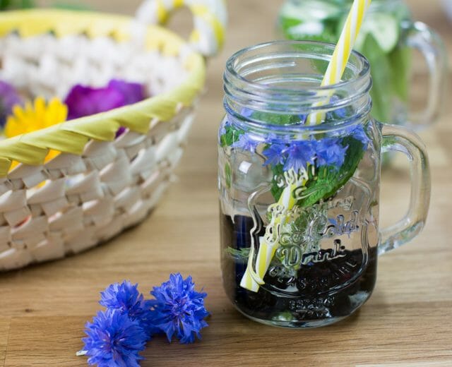 Kornblumen-im-Glas-mit-Brombeeren-Infused-Water-blau Letní limonáda s bylinkami podávaná ve sklenici s brčkem