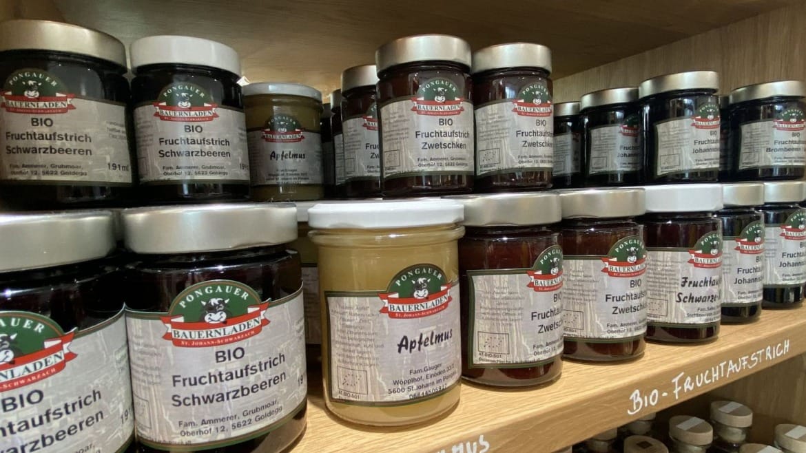 Regály plné regionálních potravin, jako jsou medy, marmelády, ovocné pyré a mnoho dalšího ve farmářském obchodě v St. Johann v Salcbursku