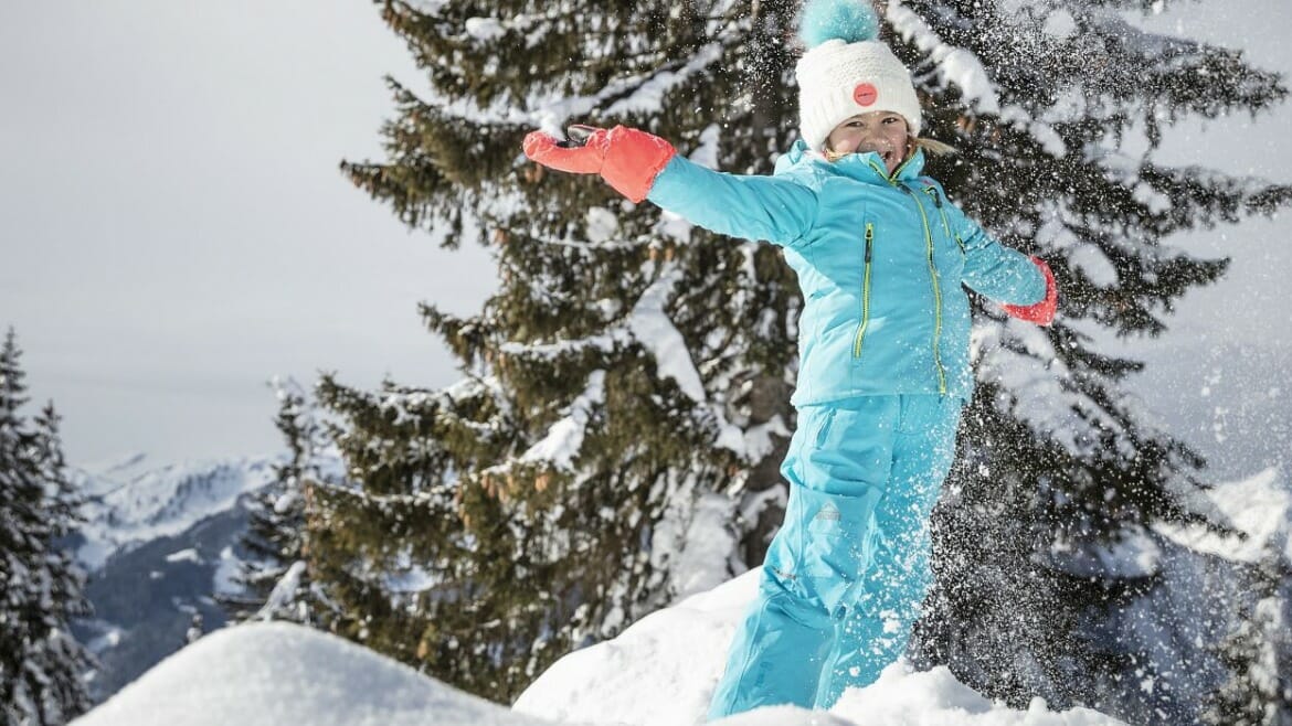 Dívka dovádí ve sněhu v St. Johann v Salcbursku, kde se konají pro děti speciální zábavné týdny JoKiWo.