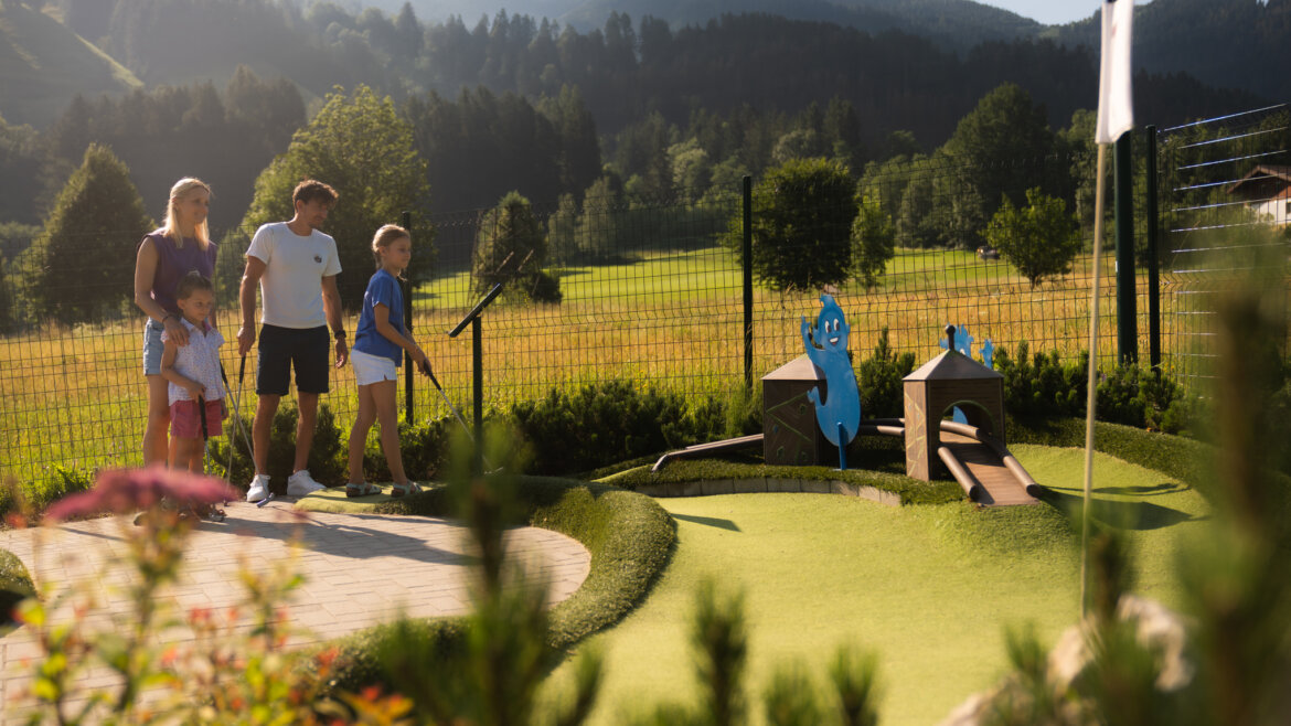 Na minigolfu s dominantami St. Johann v Salcbursku © JOsalzburg.com, Klaus Listl Čtyřčlenná rodina si za slunečného dne v St. Johannu užívá minigolf, obklopena zelenými kopci a výhledy na hory. (Zvětšený pohled)