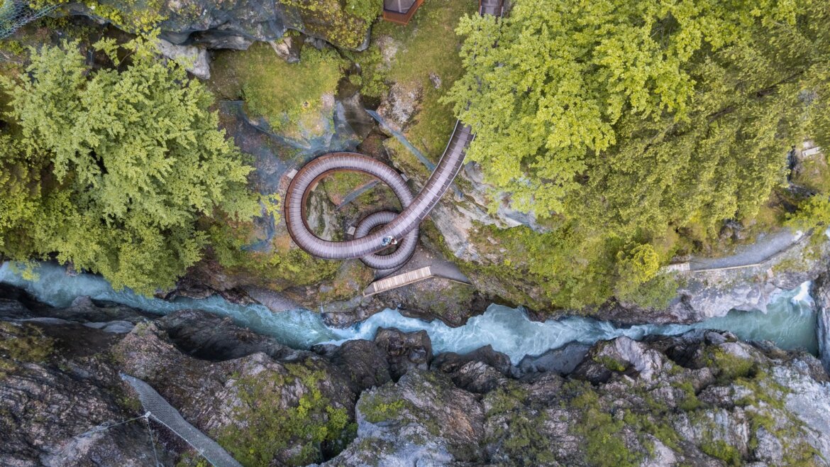 Letecký pohled na soutěsku Liechtensteinklamm s řekou v St. Johann turistika, orámovanou skalami a svěžími zelenými stromy.