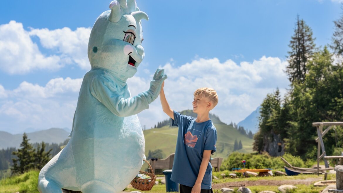 Maskot hory Geisterberg © JOsalzburg Chlapec s modrým maskotem venku během rodinné dovolené v St. Johann léto za slunečného dne. (Zvětšený pohled)