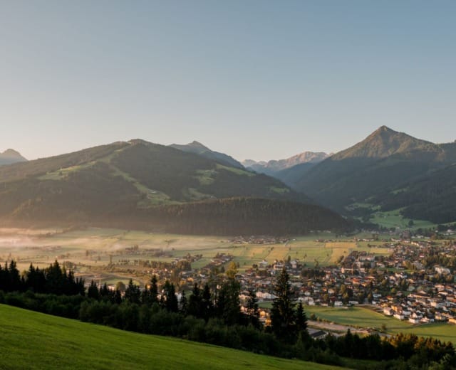blick-auf-altenmarkt Malé městečko v zeleném údolí s horami v pozadí pod jasnou oblohou.