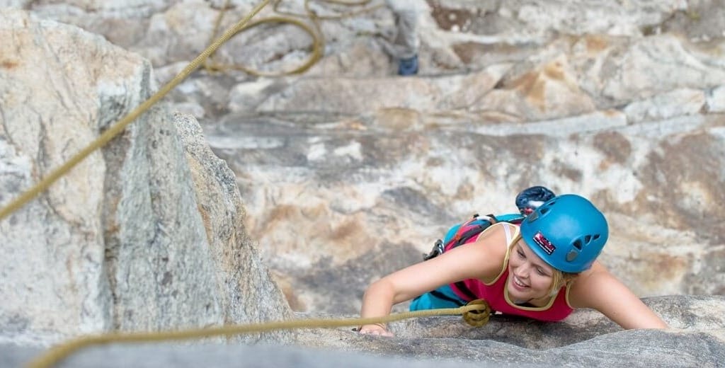 Dívka jištěná lanem zdolává skalní stěnu na jedné z lezeckých tras v Gasteinu