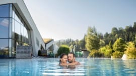 Pár se objímá ve vodě jednoho z bazénů v termálních lázních Erlebnis-Therme Amadé v Altenmarkt-Zauchensee