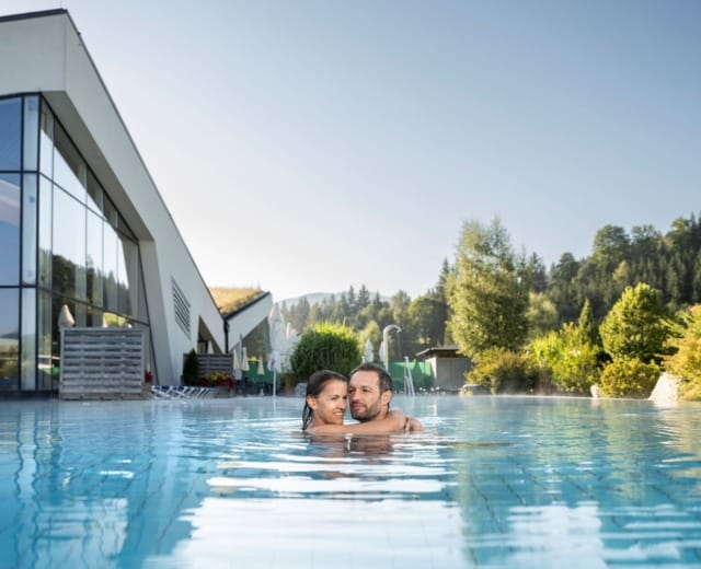 erholung-erlebnis-therme-amade-in-altenmarkt-zauchensee Pár se objímá ve vodě jednoho z bazénů v termálních lázních Erlebnis-Therme Amadé v Altenmarkt-Zauchensee
