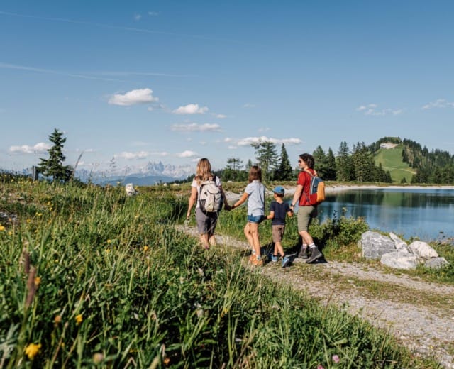 Rodina na výletě u nádrže v horách v oblasti Alpendorf v St. Johann v Salcbursku