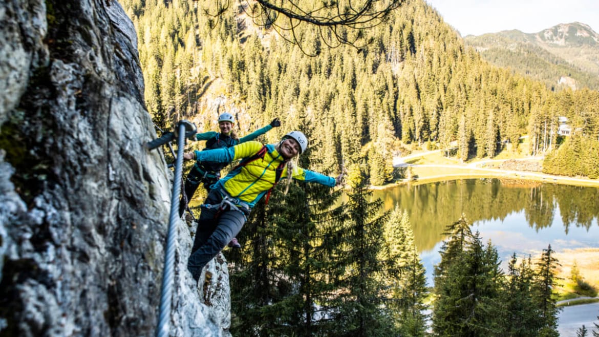 Dvojice mává z ferraty v lezeckém centru nad jezerem Seewand 
