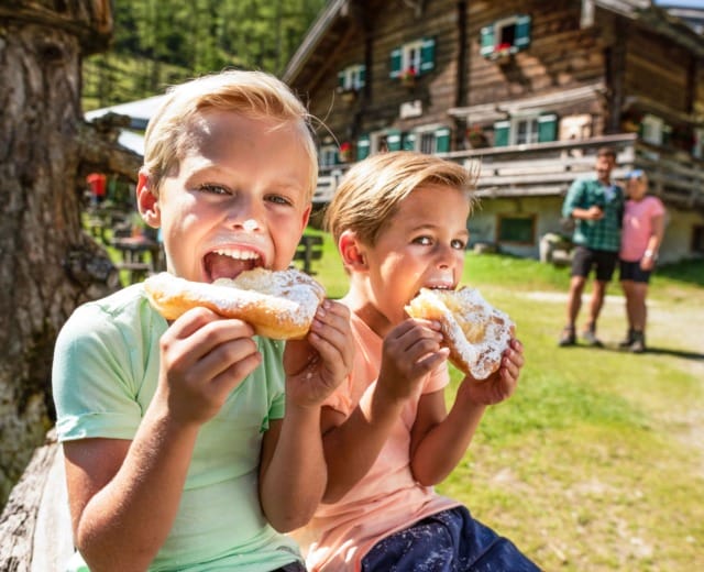 Děti si pochutnávají na sladkých, bohatě pocukrovaných koblihách Krapfen