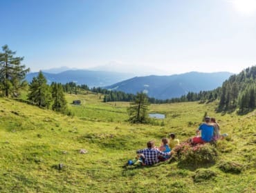 panorama_lackenalm_mit_menschen Turisté ve Flachau odpočívají na zelené horské louce Lackenalm a dívají se na hory