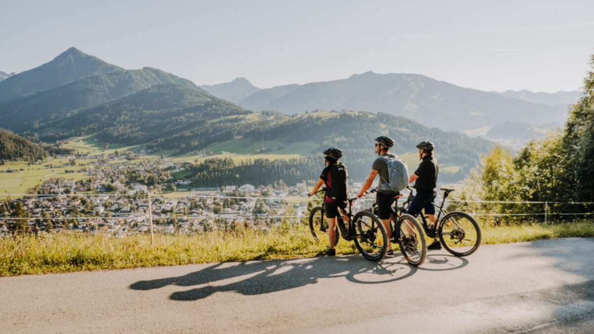 Tři cyklisté si na trase dělají přestávku, aby se pokochali výhledem z vrcholu na město Altenmarkt.