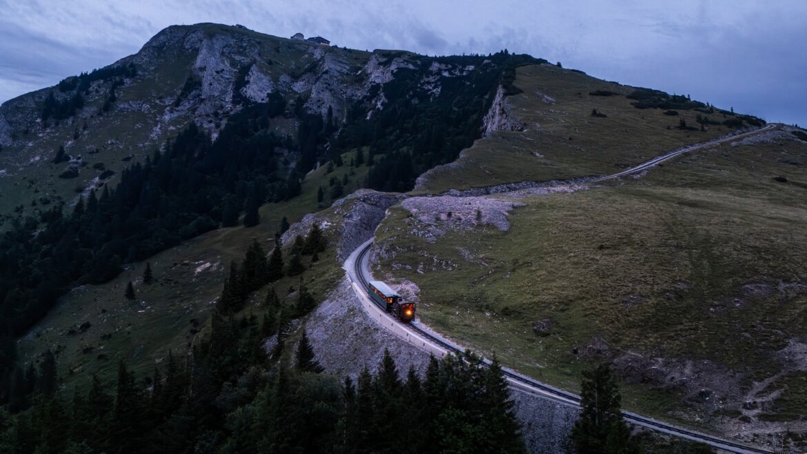 Večerní jízda zubačky SchafbergBahn na vrchol Schafbergu © Salzburg AG Tourismus GmbH Zubačka SchafbergBahn při večerní jízdě serpentinami na horu Schafberg v Salzkammergut (Zvětšený pohled)