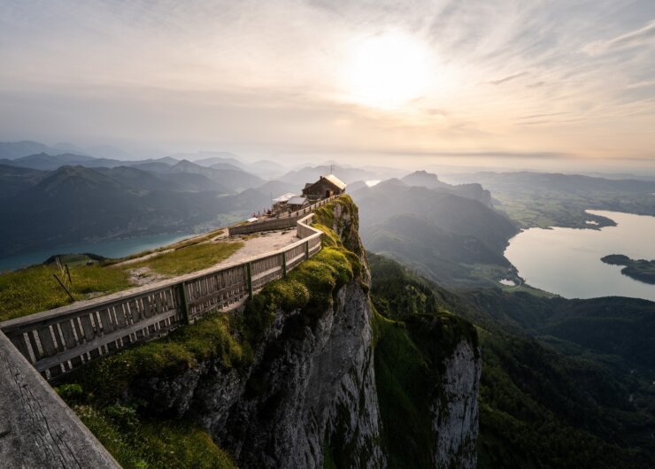 Himmelspforte Schafbergspitze Dřevěný plot lemuje horskou cestu k chatě Himmelspforte s výhledem na jezera při západu slunce.