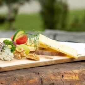 Dřevěné prkénko obložené sýry, sýry a zeleninou ochutnáte na kulinářských výletech v Gasteinu