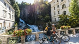 Cyklisté pozorují z mostu mohutný vodopád v centru města Bad Gastein