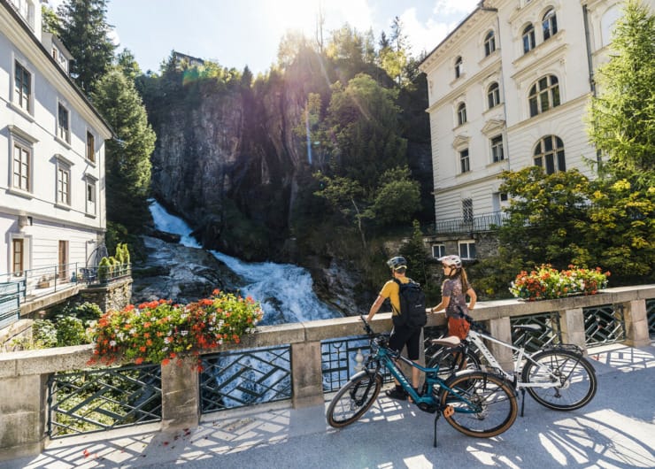 Cyklisté pozorují z mostu mohutný vodopád v centru města Bad Gastein