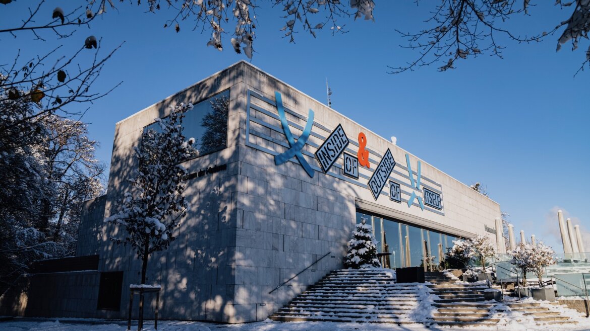 Budova Muzea moderního umění se zasněženou zemí a stromy. (Zvětšený pohled)