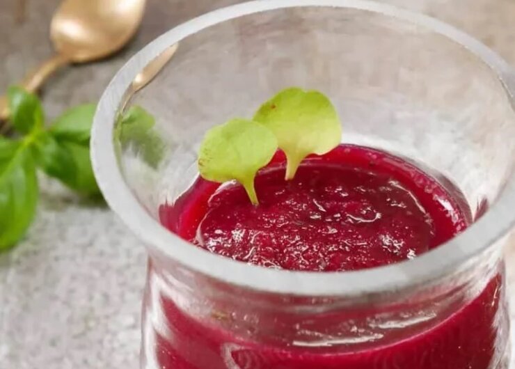 Zdravé a zářivě červené smoothie z červené řepy ve sklenici ozdobené zelenými lístky