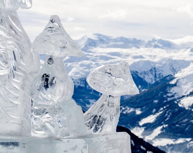 Socha z ledu v podobě křišťálově se třpytících hub na festivalu Art on snow a výhled na zasněžené hory okolo Gasteinu