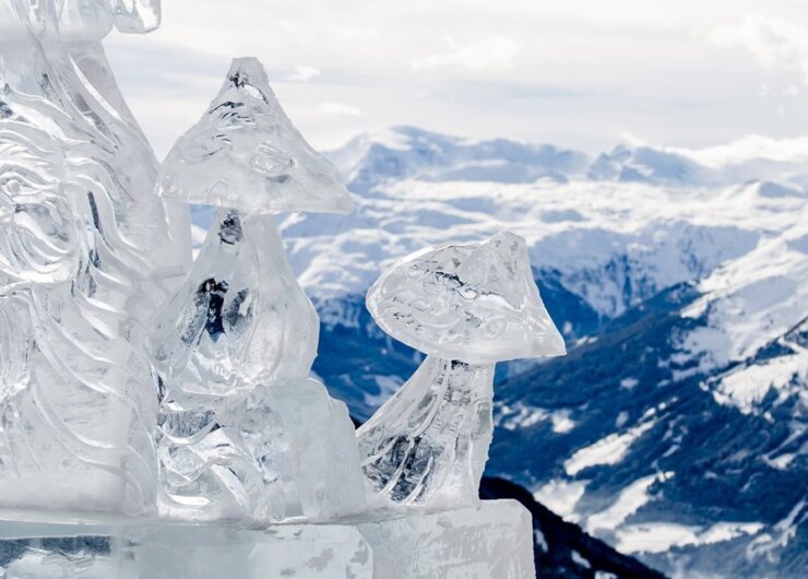 Socha z ledu v podobě křišťálově se třpytících hub na festivalu Art on snow a výhled na zasněžené hory okolo Gasteinu