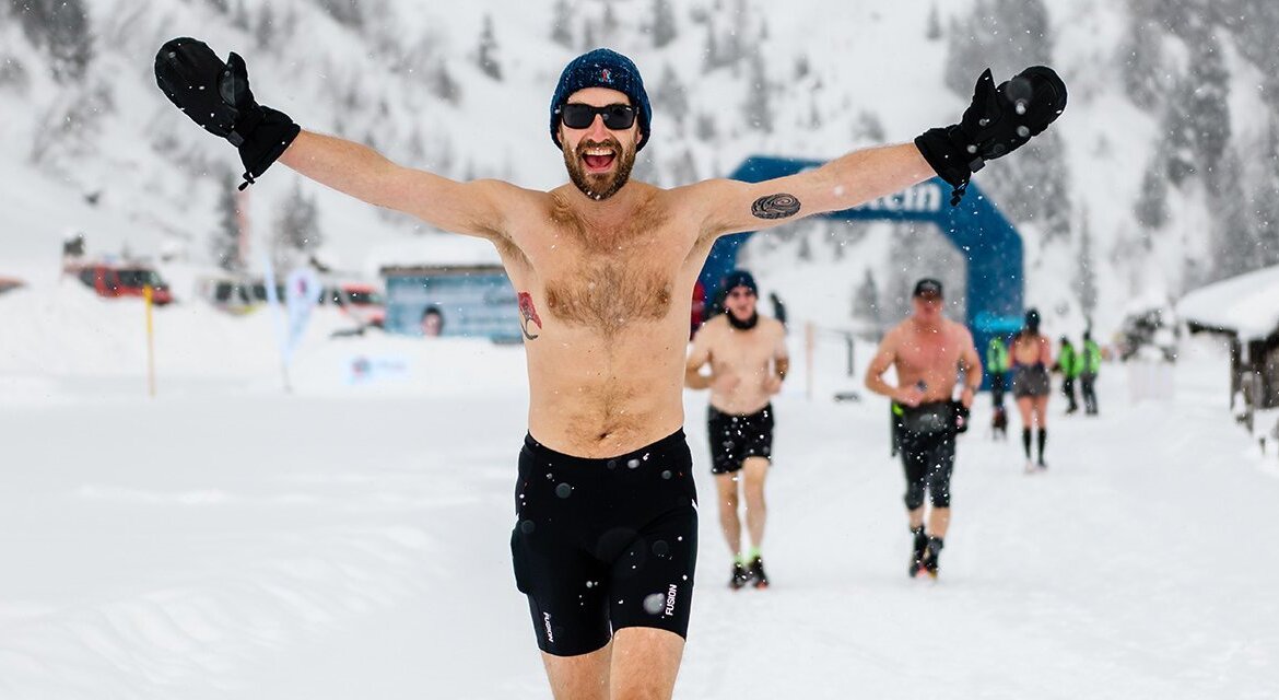 Běh, jízda na běžkách a plavání, to jsou disciplíny zimního závodu pro otužilce Ice4Life v Gasteinu. Jeden ze šťastných závodníků běží v krátkých kalhotách zasněženou trasou